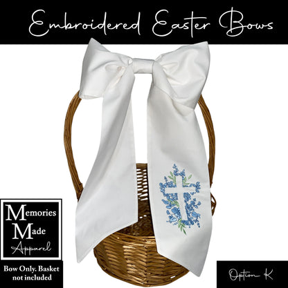 Embroidered Easter bow that is white in color. There is a floral cross design on  the right bow tail in the colors blue and green. The background of the picture is white, and there is information in the corners. The information states: Bow only, basket not include. It shows that the option to order is "K".