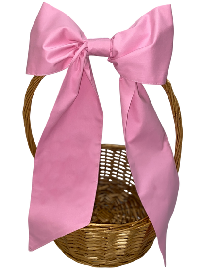 Wicker basket with a large pink bow on a white background