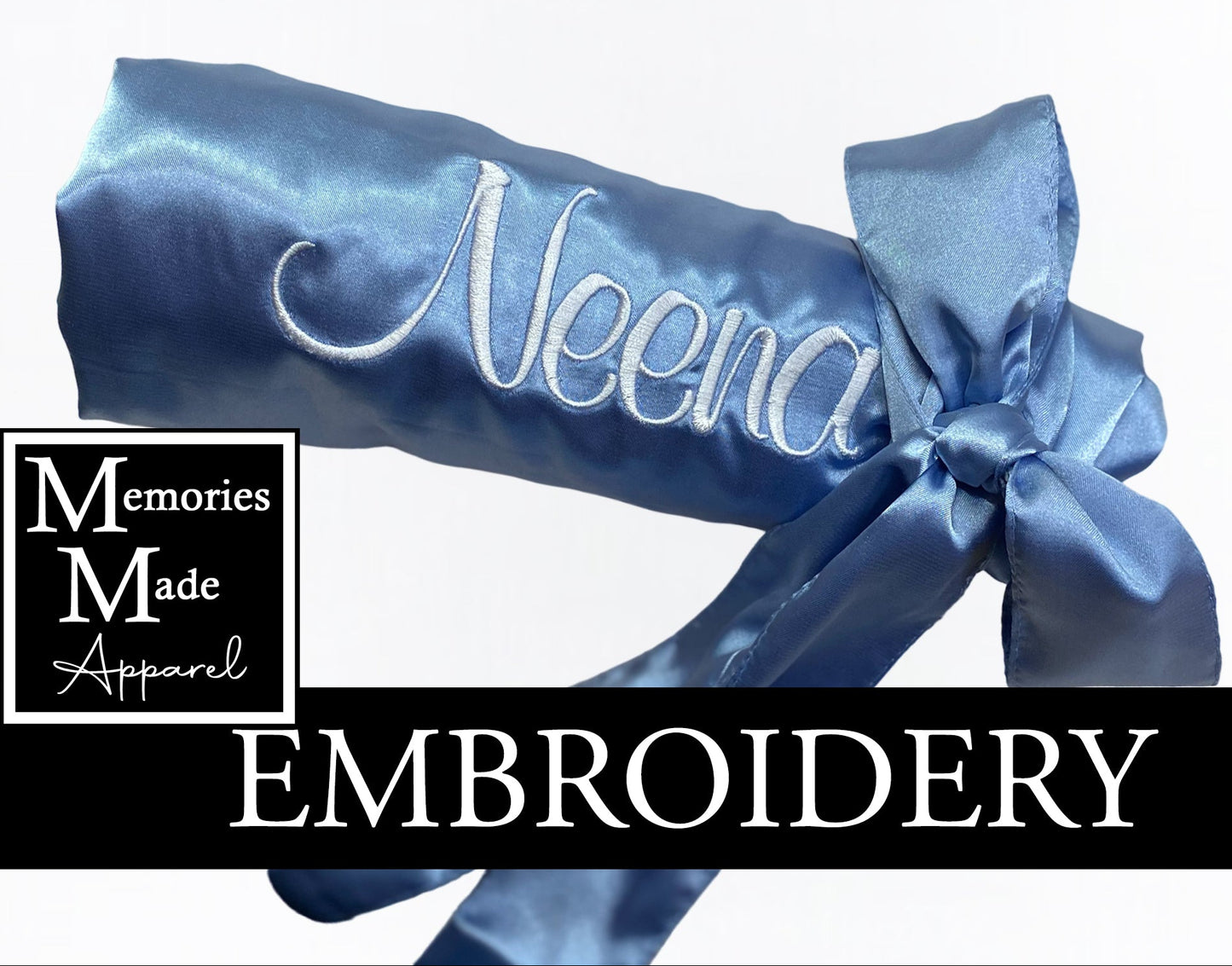 Light Blue satin robe with custom embroidery on the left chest in white thread. The robe is rolled up and tied with the matching robe belt. The logo for Memories Made Apparel is on the left side of the picture. The word "Embroidery" is on a banner in the lower portion of the picture. 